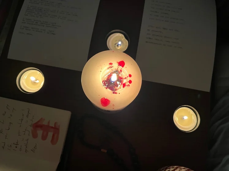 View of the three prayer candles and the central sacrifice candle from above. There is quite a bit of blood on the sacrifice candle, including some fresh one from today. My sacrifice book is open, a prayer is written in it, and her symbol drawn with my blood.