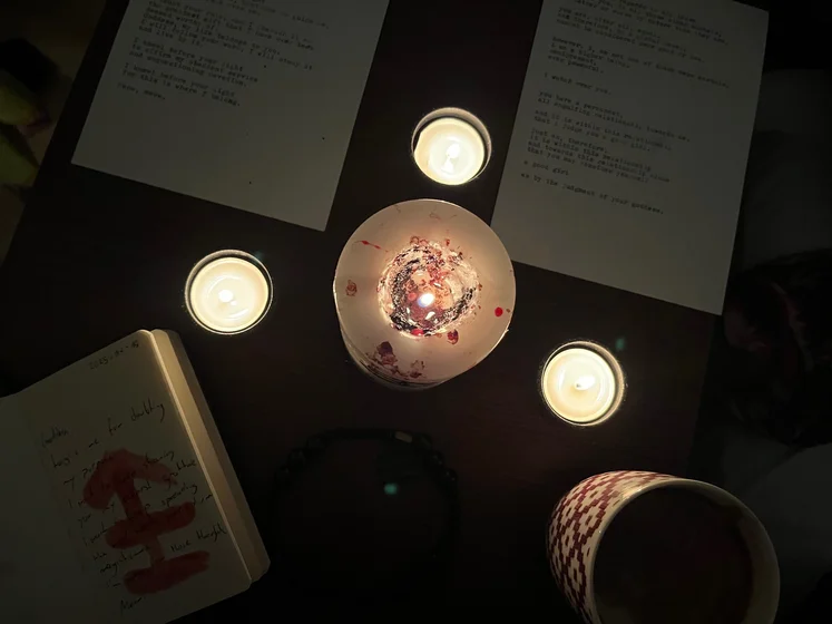 View of the three prayer candles and the central sacrifice candle from above. There is quite a bit of blood on the sacrifice candle, including some fresh one from today. My sacrifice book is open, a prayer is written in it, and her symbol drawn with my blood.