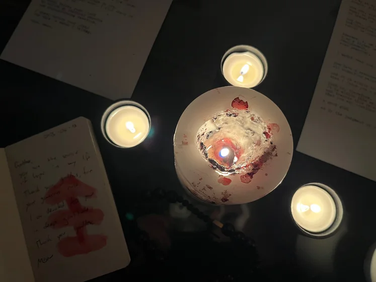 View of the three prayer candles and the central sacrifice candle from above. There is quite a bit of blood on the sacrifice candle, including some fresh one from today. My sacrifice book is open, a prayer is written in it, and her symbol drawn with my blood.