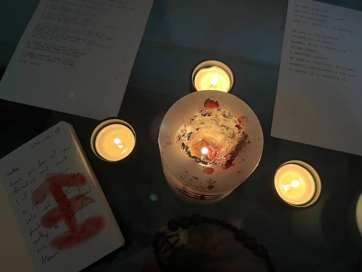 View of the three prayer candles and the central sacrifice candle from above. There is quite a bit of blood on the sacrifice candle, including some fresh one from today. My sacrifice book is open, a prayer is written in it, and her symbol drawn with my blood.