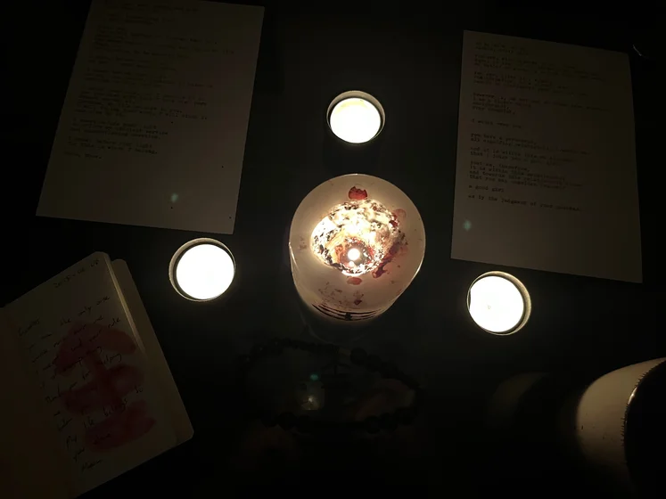 View of the three prayer candles and the central sacrifice candle from above. There is quite a bit of blood on the sacrifice candle, including some fresh one from today. My sacrifice book is open, a prayer is written in it, and her symbol drawn with my blood.
