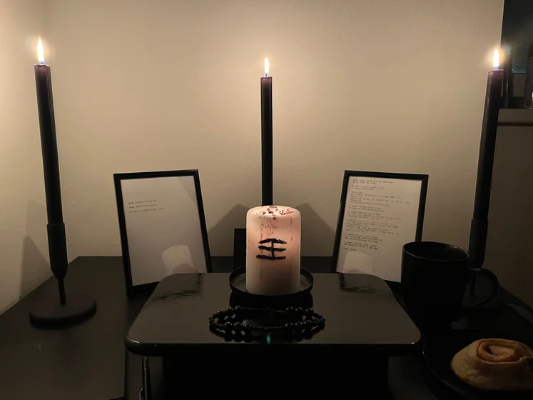 Ritual setup: Sacrifice book, prayer candles, the sacrifice candle in the center showing her holy sign, my prayer beads in front, and a cup of cocoa. Two pages written with a typewriter in the background.