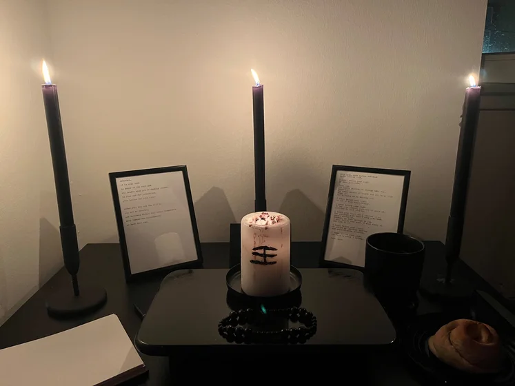 Ritual setup: Sacrifice book, prayer candles, the sacrifice candle in the center showing her holy sign, my prayer beads in front, and a cup of cocoa. Two pages written with a typewriter in the background.
