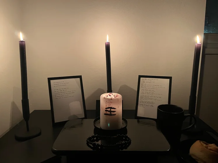Ritual setup: Sacrifice book, prayer candles, the sacrifice candle in the center showing her holy sign, my prayer beads in front, and a cup of cocoa. Two pages written with a typewriter in the background.