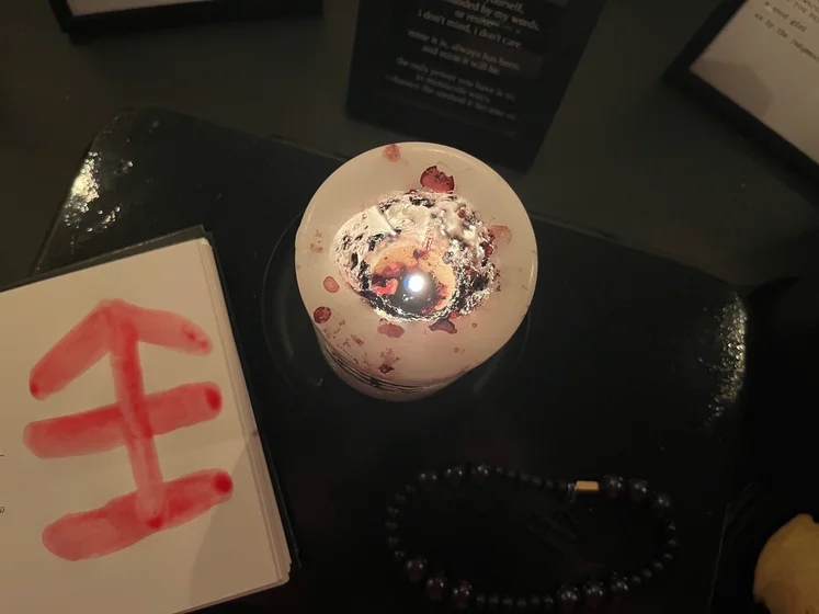 View of the three prayer candles and the central sacrifice candle from above. There is quite a bit of blood on the sacrifice candle, including some fresh one from today. My sacrifice book is open, a prayer is written in it, and her symbol drawn with my blood.