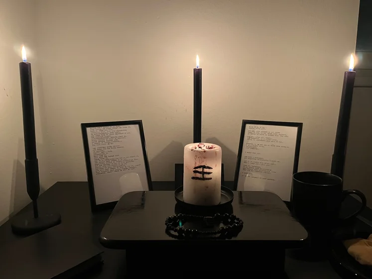 Ritual setup: Sacrifice book, prayer candles, the sacrifice candle in the center showing her holy sign, my prayer beads in front, and a cup of cocoa. Two pages written with a typewriter in the background.