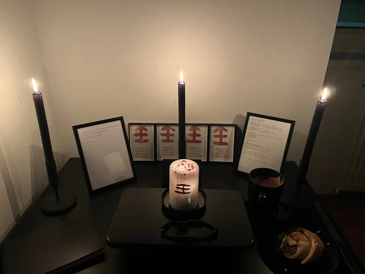 Ritual setup: Sacrifice book, prayer candles, the sacrifice candle in the center showing her holy sign, my prayer beads in front, and a cup of cocoa. Two pages written with a typewriter in the background.