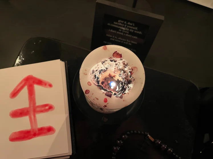View of the three prayer candles and the central sacrifice candle from above. There is quite a bit of blood on the sacrifice candle, including some fresh one from today. My sacrifice book is open, a prayer is written in it, and her symbol drawn with my blood.
