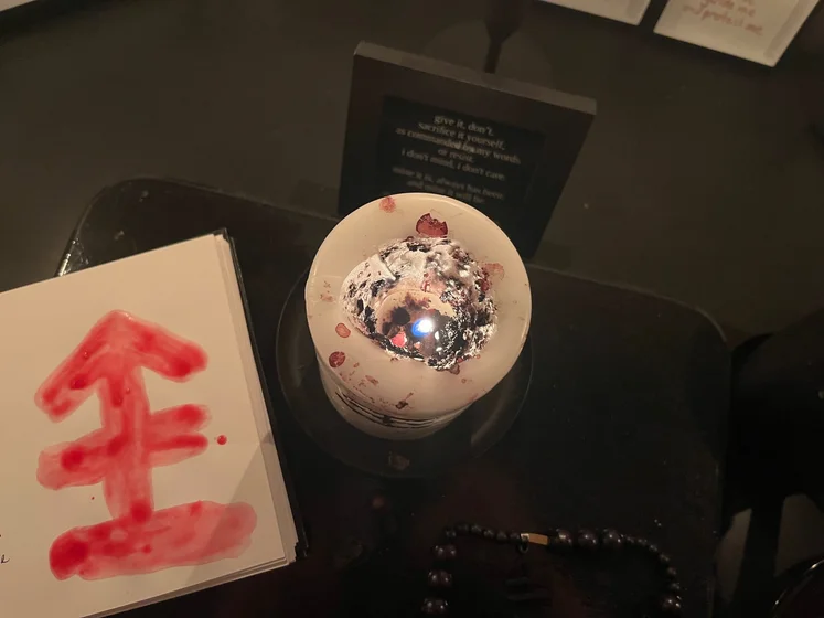 View of the three prayer candles and the central sacrifice candle from above. There is quite a bit of blood on the sacrifice candle, including some fresh one from today. My sacrifice book is open, a prayer is written in it, and her symbol drawn with my blood.