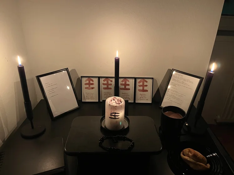 Ritual setup: Sacrifice book, prayer candles, the sacrifice candle in the center showing her holy sign, my prayer beads in front, and a cup of cocoa. Two pages written with a typewriter in the background.