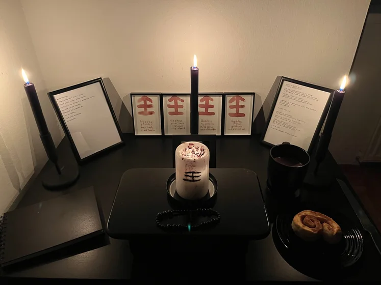 Ritual setup: Sacrifice book, prayer candles, the sacrifice candle in the center showing her holy sign, my prayer beads in front, and a cup of cocoa. Two pages written with a typewriter in the background.