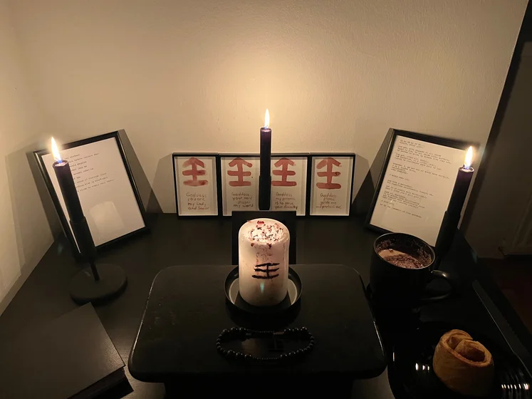 Ritual setup: Sacrifice book, prayer candles, the sacrifice candle in the center showing her holy sign, my prayer beads in front, and a cup of cocoa. Two pages written with a typewriter in the background.