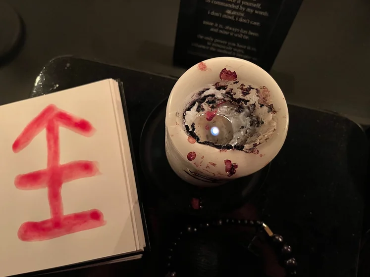 View of the three prayer candles and the central sacrifice candle from above. There is quite a bit of blood on the sacrifice candle, including some fresh one from today. My sacrifice book is open, a prayer is written in it, and her symbol drawn with my blood.