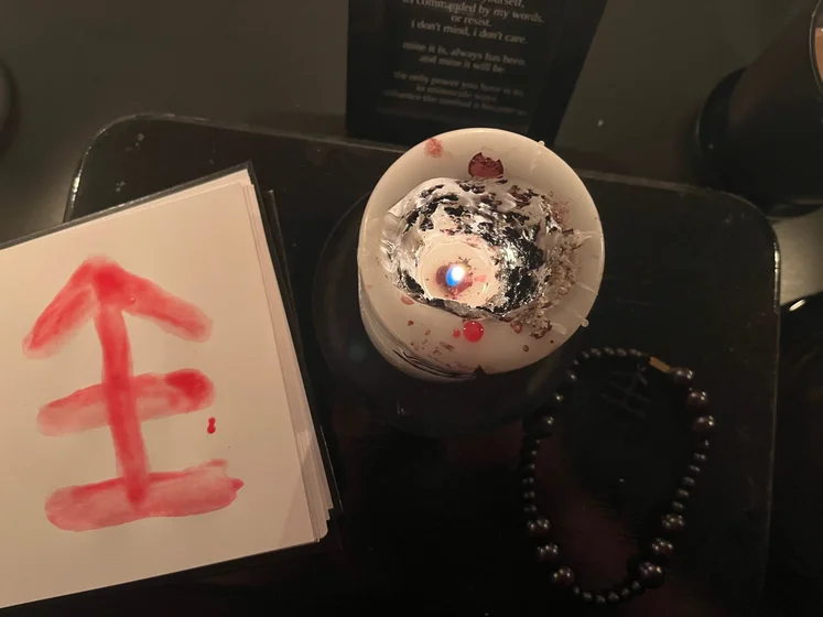 View of the three prayer candles and the central sacrifice candle from above. There is quite a bit of blood on the sacrifice candle, including some fresh one from today. My sacrifice book is open, a prayer is written in it, and her symbol drawn with my blood.