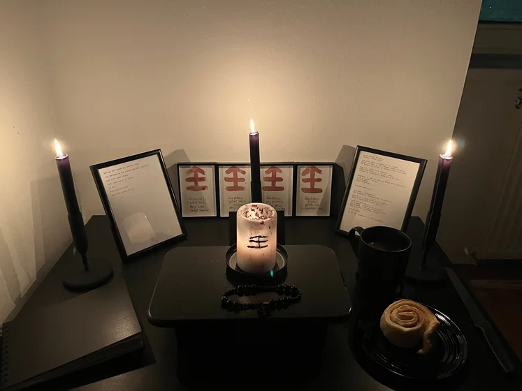 View of the three prayer candles and the central sacrifice candle from above. There is quite a bit of blood on the sacrifice candle, including some fresh one from today. My sacrifice book is open, a prayer is written in it, and her symbol drawn with my blood.